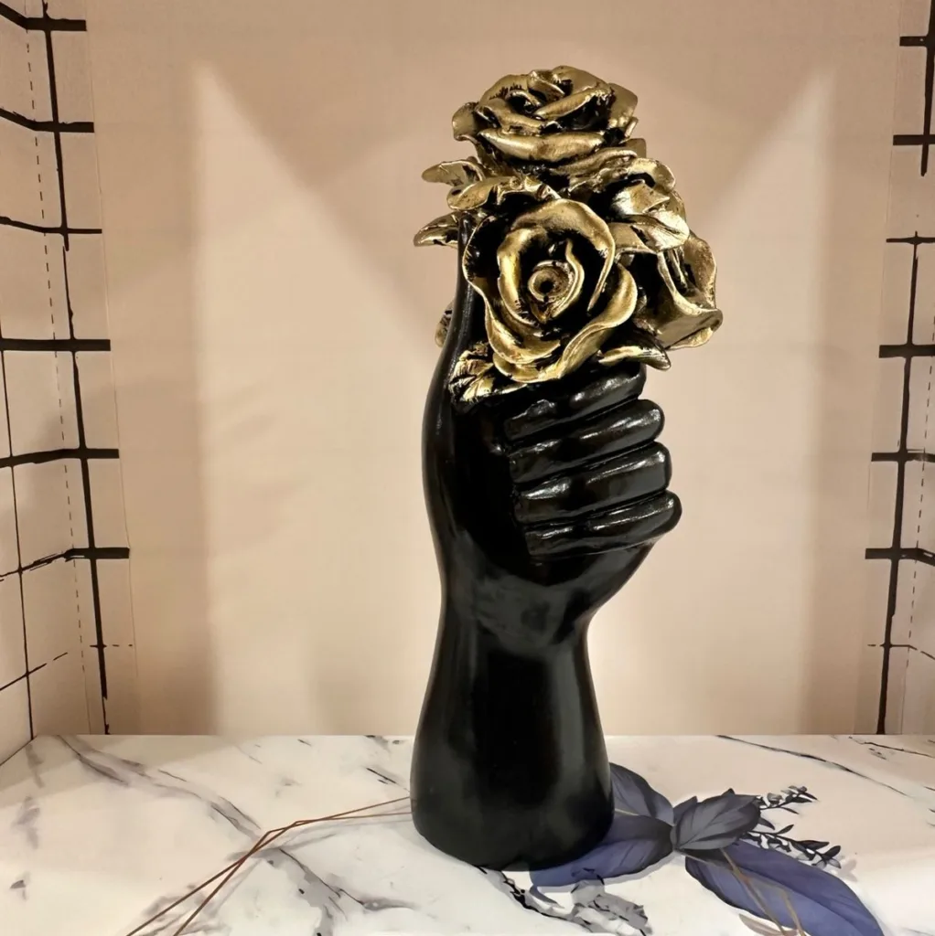 Hand holding rose sculpture in black and gold luxury finish
